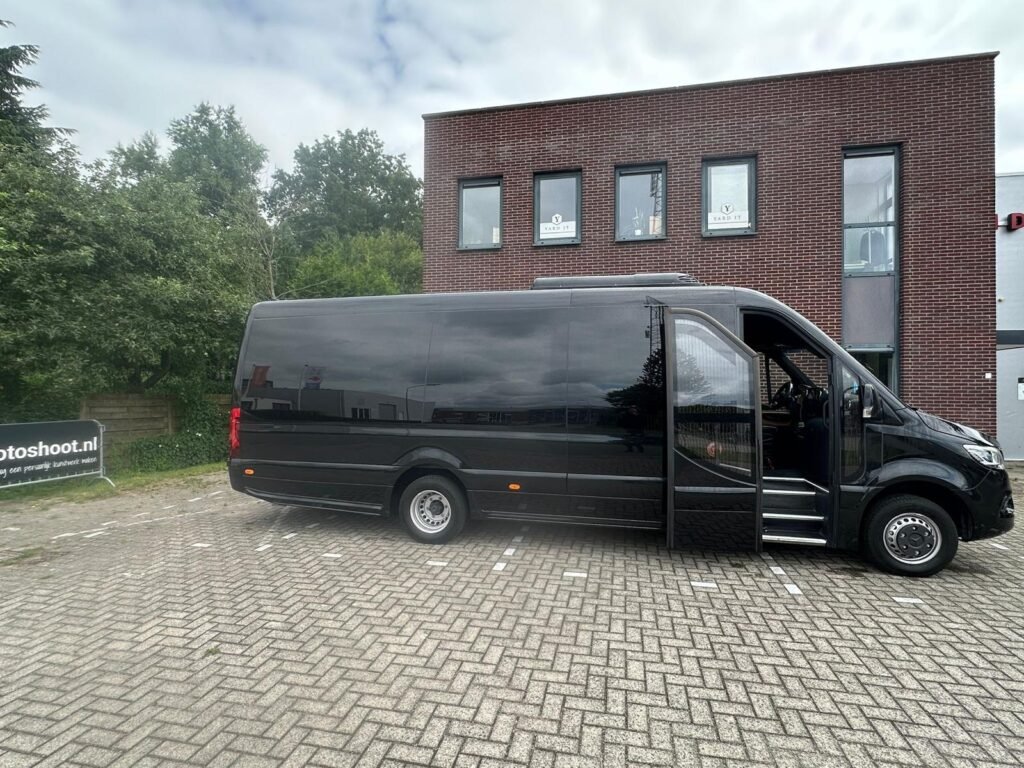 Large black Mercedes Sprinter passenger van parked on a brick lot
