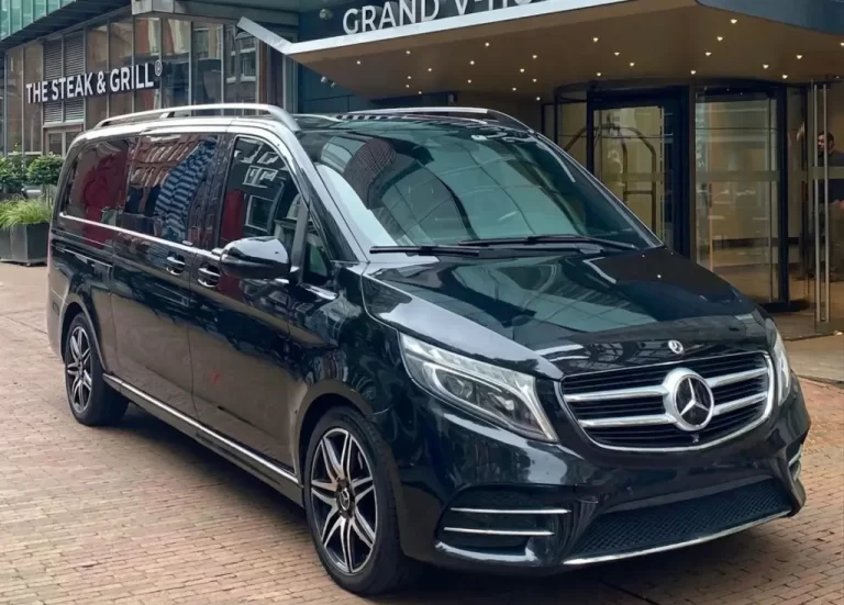 Black Mercedes van parked outside hotel.