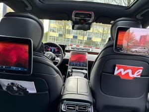 Luxury Mercedes E-Class taxi interior with premium leather seats, panoramic sunroof, rear entertainment screens, and modern dashboard in Amsterdam.